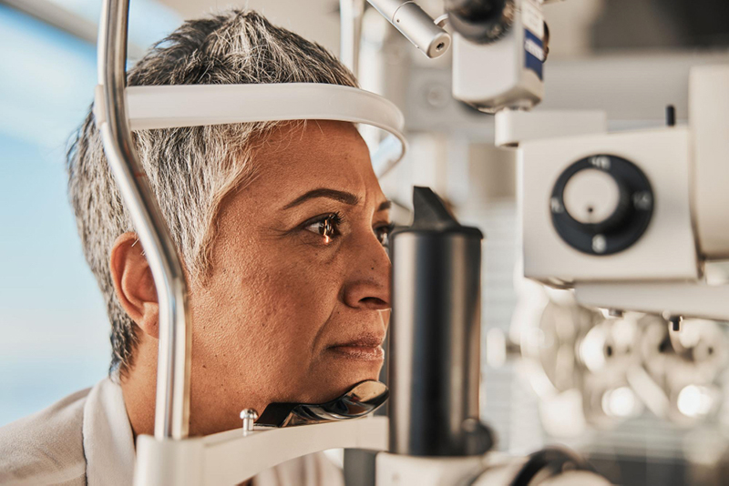 A woman undergoing an eye examination for glaucoma treatment using specialized ophthalmic equipment.